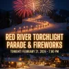 A promotional graphic for the Red River Torchlight Parade & Fireworks. The image features a night scene of a snowy ski mountain with a line of skiers holding bright torches winding down the slope, capped by large red and gold fireworks in the sky. Below, a snowy village glows with warm window lights. Large text overlays the image reading: "RED RIVER TORCHLIGHT PARADE & FIREWORKS" followed by the date and time: "TONIGHT! FEBRUARY 21, 2026 - 7:00 PM.