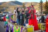 A Mardi Gras krewe queen in a red gown rides a parade float in Red River.
