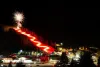 A wide view of the torchlight parade and fireworks over Red River at night.