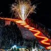 Torchlight trail switchbacks glow beneath fireworks at Red River Ski Area.