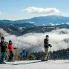 Skiers pause on a snowy ridge at Red River Ski Area with Wheeler Peak and the Sangre de Cristo range behind them.