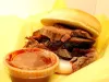 A sliced brisket sandwich with a cup of barbecue sauce at Shotgun Willie's Cafe in Red River.