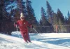 Judy Miller skiing at Powder Puff Mountain in Red River in the 1970s, in a red ski suit with a rope tow behind her.
