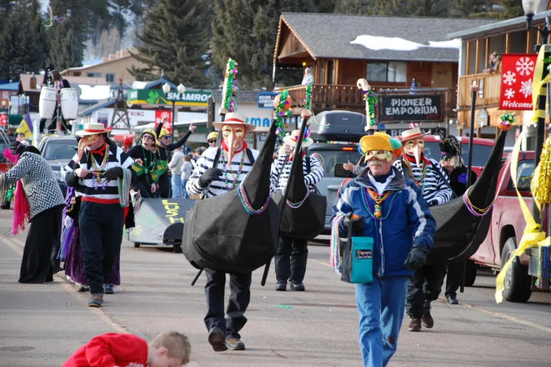 Costumed Mardi Gras krewe members parade a gondola down Main Street in Red River during Mardi Gras in the Mountains.