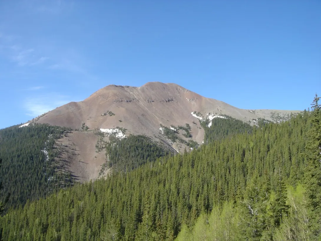 Baldy Mountain's bare, treeless summit rising above pine forest at Philmont Scout Ranch, seen from Copper Park camp.