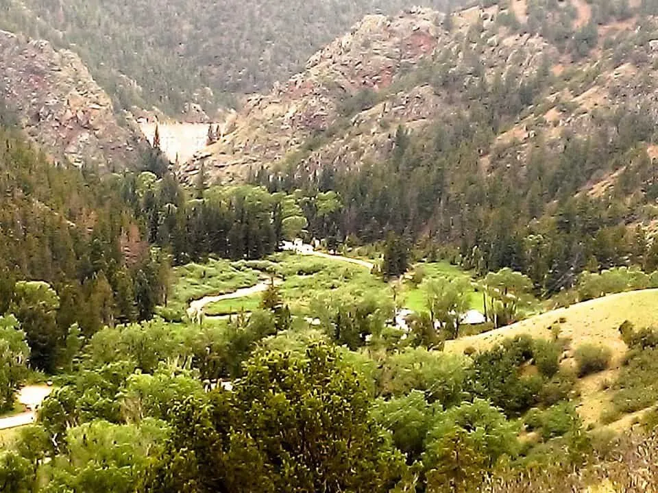The Cimarron River winding through Cimarron Canyon, with Eagle Nest Dam visible in the distance at the head of the canyon.