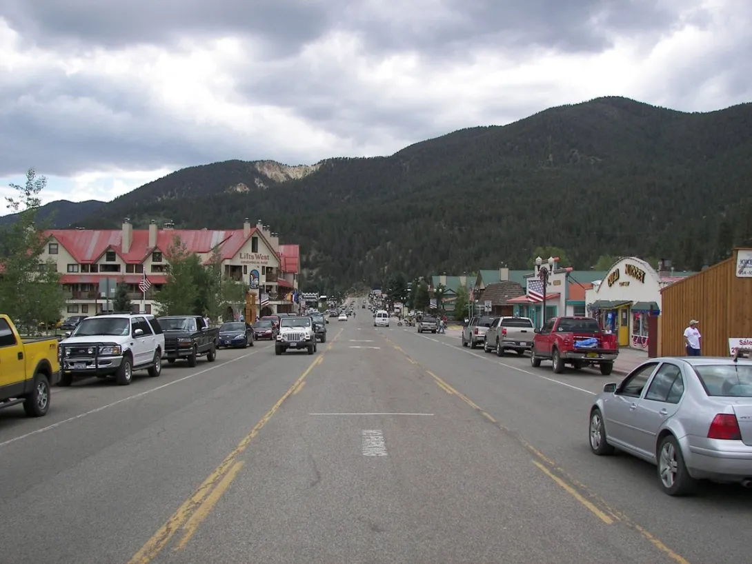 Main Street in Red River, New Mexico looking northwest, with the Lifts West lodge on the left and the forested ski mountain rising behind town.