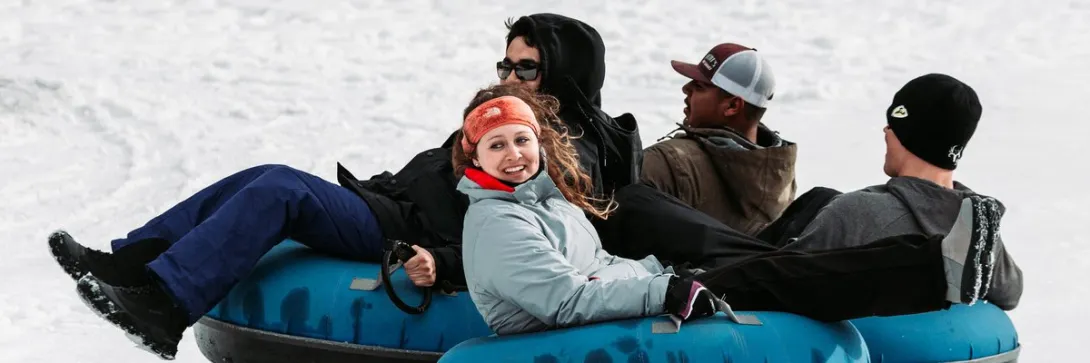 A group rides linked snow tubes at Red River Ski and Summer Area.