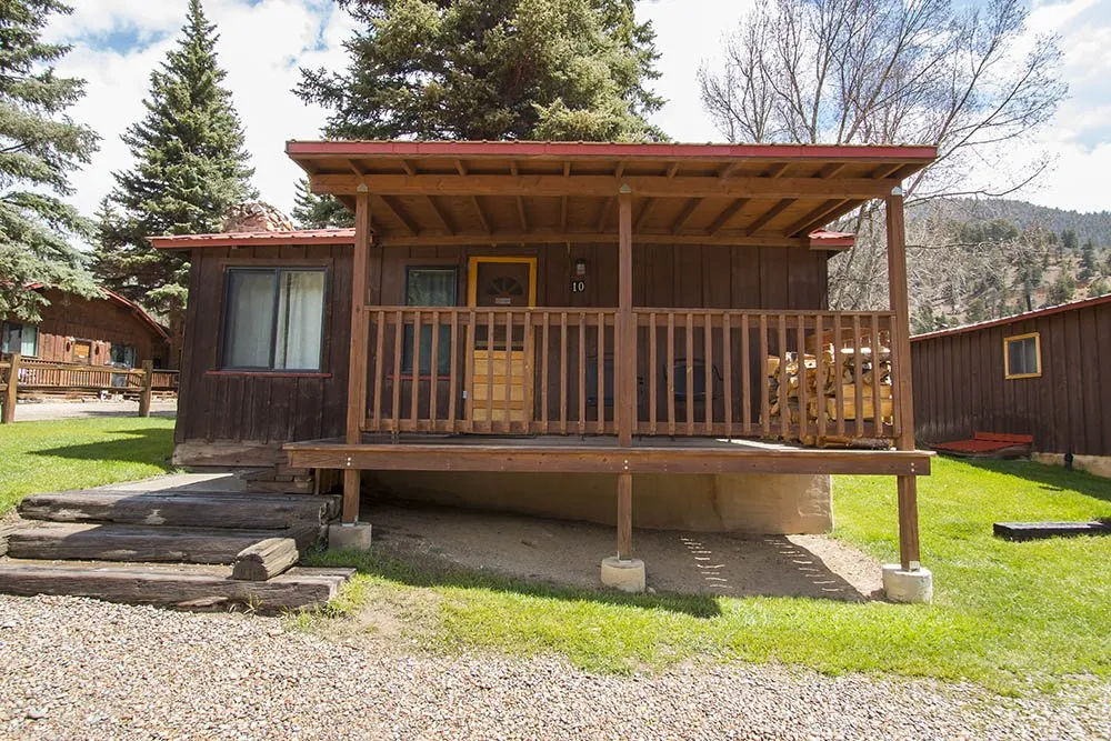 A rustic wooden cabin with a covered porch at Rio Colorado Cabins in Red River.