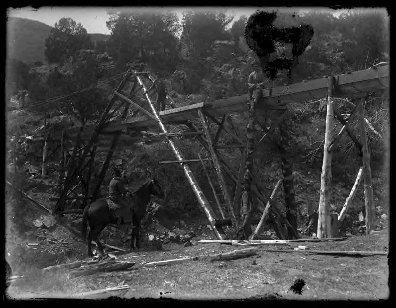 The underside of a wooden mining flume in the mountains near Red River in the 1910s.
