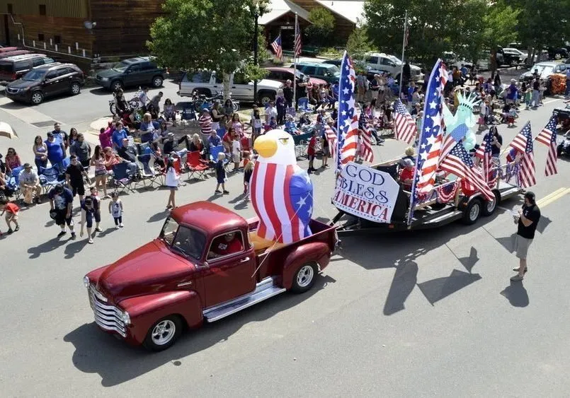 A vintage red pickup leads a patriotic float down Main Street during Red River's Fourth of July parade.