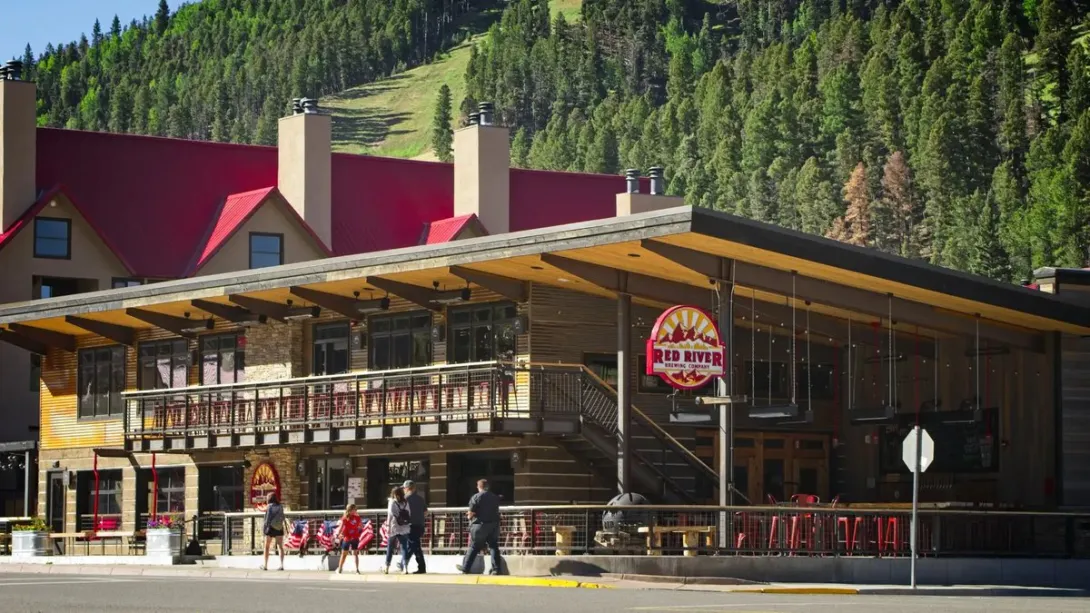 The Red River Brewing Company building and patio on West Main Street, with the ski slopes rising behind it.