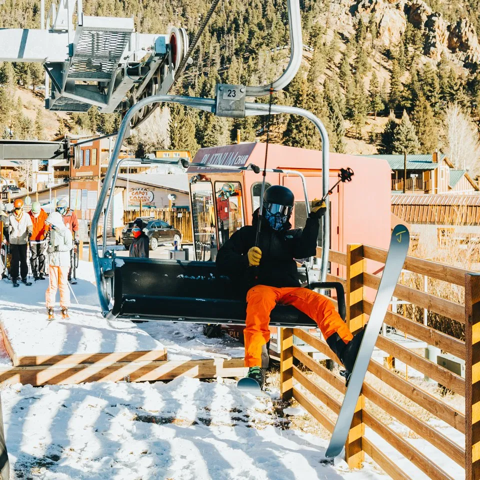A snowboarder loads the Platinum Chair at Red River Ski and Summer Area above the town of Red River.
